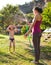 Mother sprays a child with a hose in the courtyard of the house, Boy drenched in water on a hot sunny day