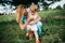 mother squatting and hugging daughter in field
