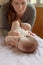 Mother stands next to the child. Massage for the baby. Four month old baby smiling doing gymnastics