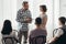 Mother stands next to handsome therapist talking to her teenage child during group meeting