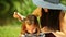 Mother in straw hat combing daughter in the park