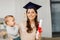 Mother student with baby boy and diploma at home