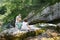 Mother taking a snapshot of kids on a family trip by a mountain stream