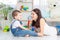 The mother talks to the baby boy or plays at home with educational toys in the children`s room. A happy, loving family