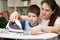 A mother teaches her 4-year-old son to iron clothes. Helping mom with the housework, a little helper