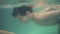 Mother teaches her son swimming under the water in indoors swimming pool. Underwater shooting, young boy rows under the