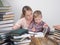 Mother teaches son to read among the stacks of books