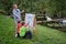 Mother teaches to paint with two boys pupils. Woman teacher artist paints with children on paper nature and trees by the river