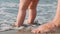 Mother teaching baby to walk at beach. Kids feet on sand beach