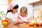 Mother teaching child making salad in kitchen. Mom and kid chopping vegetable on cutting board with knife. Cooking concept of