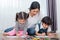 Mother teaching children in drawing class. Daughter and son painting with colorful crayon color in home. Teacher training students