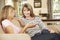 Mother With Teenage Daughter Sitting On Sofa At Home Chatting