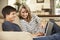 Mother With Teenage Son Sitting On Sofa At Home Using Laptop