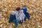 Mother and three children sitting on fallen leaves in autumn forest. Family walking in fall Park