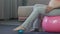 Mother-to-be sitting on fitness ball, massaging feet with rubber ball, body care