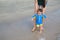 Mother training baby to walking first steps on the beach
