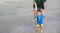 Mother training baby to walking first steps on the beach