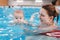 Mother traning her newborn baby to float in swimming pool