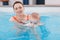 Mother traning her newborn baby to float in swimming pool