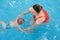 Mother traning her newborn baby to float in swimming pool