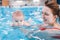 Mother traning her newborn baby to float in swimming pool