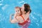 Mother traning her newborn baby to float in swimming pool