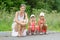 Mother and two children sitting on curb of the road waiting for the bus