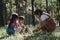 Mother and two daughters collecting firewood and kindling bonfire at camping place in forest. Family and children making campfire