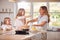 Mother And Two Daughters Making Pancakes In Kitchen At Home Together