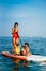Mother with two daughters stand up on a paddle board
