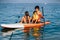 Mother with two daughters stand up on a paddle board