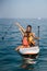 Mother with two daughters stand up on a paddle board