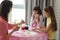 Mother and two daughters at the table paint easter eggs