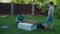 Mother and two kids has fun with big box in backyard on sunny day. Happy family plays with delivery cardboard box on the