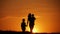 Mother and two kids silhouettes at sunset. Concept of friendly family.