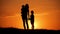 Mother and two kids silhouettes at sunset. Concept of friendly family.