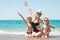 Mother and two sons in hats sitting on the beach.Summer family vacation.