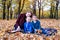 Mother and two sons relax in the park. Happy family. Yellow autumn foliage, sunny day