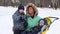 Mother and two sons wave hands, one boy kisses mother during snowfall in winter park