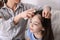 Mother using lice treatment spray on daughter`s hair indoors