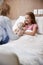 Mother Visiting Daughter Lying In Bed In Hospital Ward