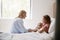 Mother Visiting Daughter Lying In Bed In Hospital Ward