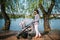 Mother walking her child near lake in city park with a beautiful pram