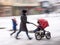 Mother walks with the child in the stroller in snowy winetr day.