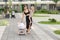 Mother walks with girl toddler outdoor. Baby doll stroller. Developmental milestones. Early years