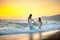 Mother walks with her daughter on the beach at sunset