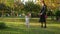 Mother walks with his lovely cute infant daughter on autumn lawn in pictorial city park with trees and fallen yellow leaves