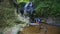 Mother Washes Daughter Hands in Fast Stream by Waterfall