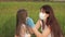 Mother wearing mask and gloves puts medical mask on child in park in summer on street during coronavirus epidemic. Mom