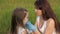 Mother wearing mask and gloves puts medical mask on child in park in summer on street during coronavirus epidemic. Mom